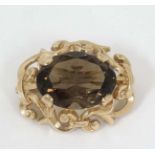 A 9ct gold brooch set with central facet cut smokey quartz within a scrolling mount.