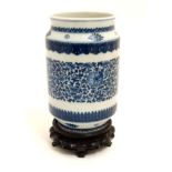 A blue and white Chinese cylinder vase having taper foot and rim on wooden stand,