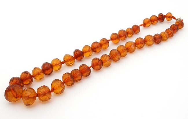 A string of graduated facet cut amber coloured beads.