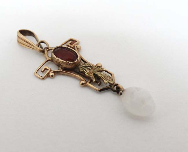 A 10k gold pedant set with red stone and white stone drop.