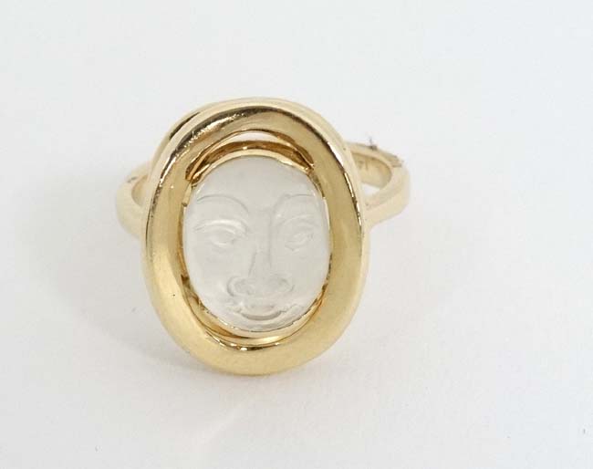 A 14k gold ring set with moonstone cabochon with man in the moon style face decoration.