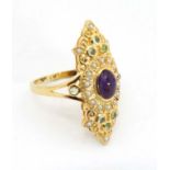 A silver gilt ring set with central amethyst cabochon bordered by seed pearls and peridot.