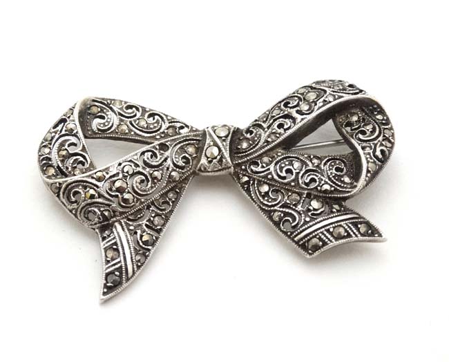 A white metal bow formed brooch set with marcasite 2" wide CONDITION: Please Note -