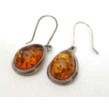 A pair of silver and white metal drop earrings set with amber.