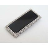 An unusual Art Deco style brooch set with central black onyx surrounded bordered by diamonds in a