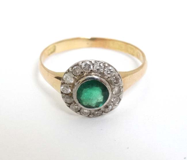 A 15ct gold ring set with central emerald bordered by diamonds CONDITION: Please