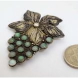 A Chinese silver lapel clip / brooch with gilt filigree decoration and set with green stone