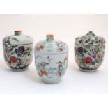 A collection of three Chinese famille rose jars and covers to include a pair decorated with