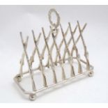 A novelty 6-slice silver plated toast rack, the bars formed as crossed guns/ rifles.