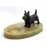 An Art Deco cast spelter model of a West Highland terrier dog with black decoration mounted upon an