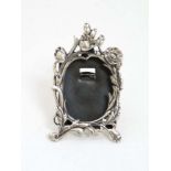 A miniature silver photograph frame with floral decoration and strut back.