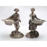 A pair of cast silver plate table salts formed as a 19thC style boy and girl each holding a basket