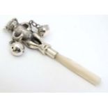 A decorative silver babies rattle with teddy bear to top, bells and mother of pearl teether handle.