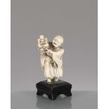 Netsuke en ivoire du Japon. Netsuke en ivoire du Japon d'un vieillard portant un Bouddha de sa