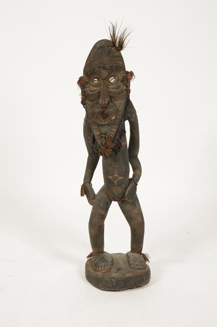 PAPUA NEW GUINEA: A standing tribal figure, the elongated face with cowry eyes, feather hair and