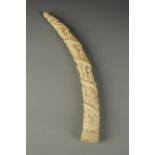 TRIBAL ART: A profusely carved ivory tusk decorated with a procession of figures rising to a deity