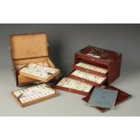 TWO CHINESE MAHJONG SETS, one with a hardwood case, 9.5" long, the other with a leather case, 9"