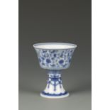 A CHINESE BLUE AND WHITE STEM CUP decorated with a band of Tibetan characters amongst flowerheads