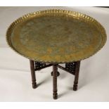 A LARGE MOORISH BRASS/COPPER TRAY-TOP TABLE, the circular top worked with portrait roundels and