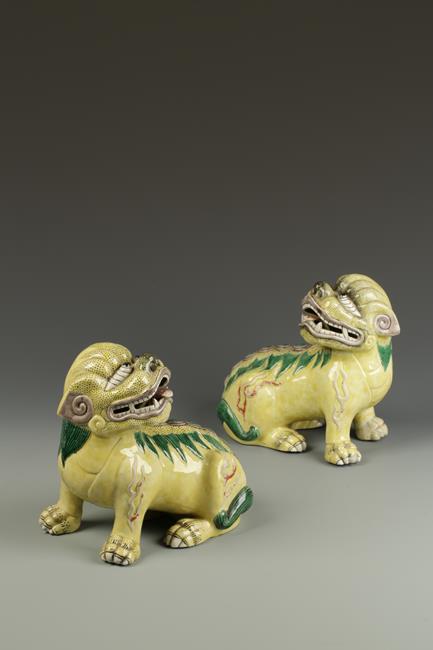 A PAIR OF BISCUIT-GLAZED BUDDHISTIC LIONS, each with its head raised and mouth open, late 19th/early