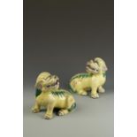 A PAIR OF BISCUIT-GLAZED BUDDHISTIC LIONS, each with its head raised and mouth open, late 19th/early