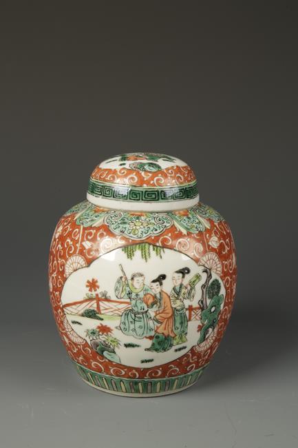 A CHINESE FAMILLE VERTE COVERED JAR decorated with panels of figures on a red ground, late Qing,