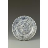 A CHINESE BLUE AND WHITE BARBED-RIM DISH decorated with a peacock amongst flowers and rocks, Ming,