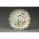 A CHINESE FAMILLE ROSE OGEE DISH decorated with flowers on a garden terrace, Qianlong, 10" dia.
