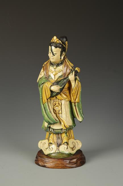 A CHINESE SANCAI-GLAZED FEMALE IMMORTAL playing a stringed instrument, Ming/Qing, 15" high