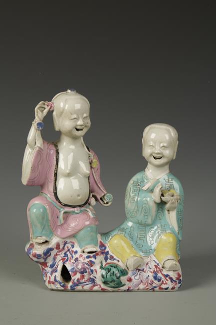 A CHINESE FAMILLE ROSE FIGURE GROUP, the male and female both laughing and seated on rockwork, Qing,