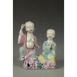 A CHINESE FAMILLE ROSE FIGURE GROUP, the male and female both laughing and seated on rockwork, Qing,