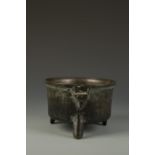 A BRONZE COOKING VESSEL with a shaped rim and three short splayed legs, possibly 17th century, 9.25"