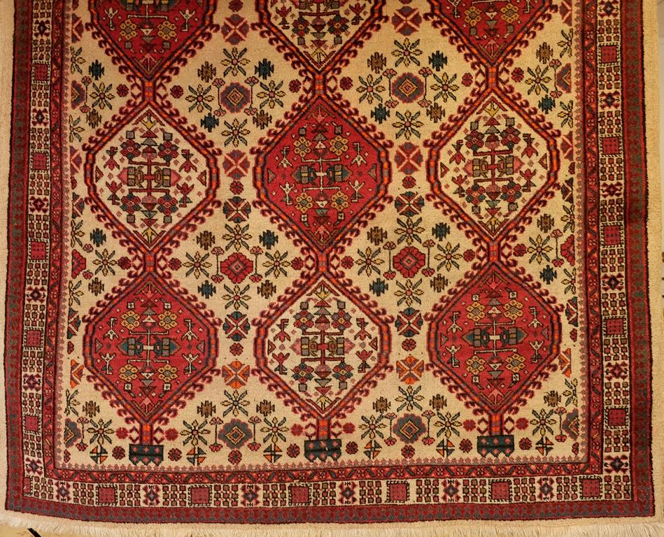 A NORTHWEST PERSIAN CARPET, the ivory ground with three rows of hexagonal medallions, with hooked