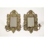 A PAIR OF BRASS WALL SCONCES with scrolling surrounds and central bevelled mirrors, with three