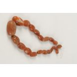 A STRING OF TWENTY CORNELIAN ANTIQUE GRADUATED BEADS, Chinese, each "cowrie"-shaped bead drilled