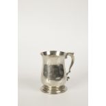 A GEORGE II MUG of baluster form with a leaf capped scroll handle and spreading circular foot,