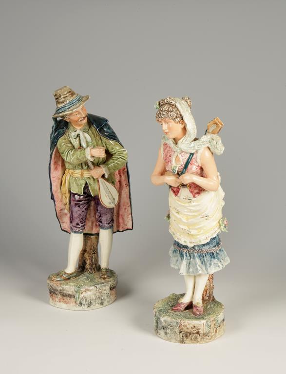 A PAIR OF ITALIANATE POTTERY FIGURES, of a male and female travelling musician, with allover poly