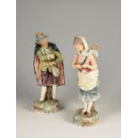 A PAIR OF ITALIANATE POTTERY FIGURES, of a male and female travelling musician, with allover poly