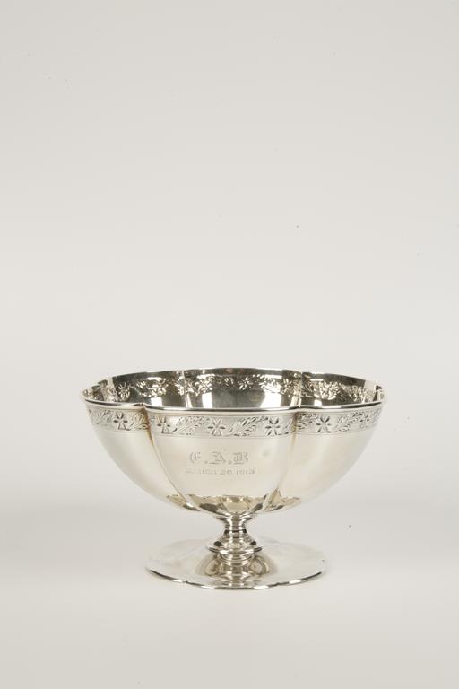 A PEDESTAL BOWL of lobed form, chased with a floral frieze, on a spreading circular foot, by Roberts