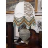 A GLASS BODIED TABLE LAMP with brass fittings, the shade with beaded decoration