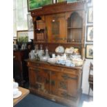 A LARGE ARTS AND CRAFTS OAK SIDEBOARD, the upper section with crenellated and carved cornice above