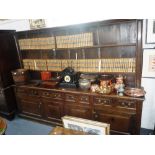 A LARGE GEORGE III OAK DRESSER with a shelved back above an arrangement of short drawers and