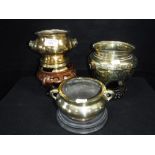 AN ORIENTAL POLISHED BRASS CENSER and two others similar, each on hardwood stands