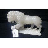 A CARVED SOAPSTONE LION with front foot resting on a ball