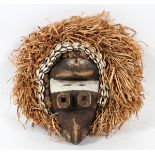 CARVED WOOD MASK, H 14", W 13"With cowrie shells and straw headdress.- For High Resolution Photos