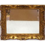 GILT WOOD BEVELLED MIRROR, H 39", W 34"Having a pierced frame with floral, leaf, and shell