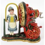 REPLICA, CAST IRON MECHANICAL BANK, H 8", W 9"depicts a girl skipping rope. Painted in red, green,