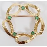 14KT YELLOW GOLD AND EMERALD BROOCH, DIA 1 1/4"A looping bushed 14kt yellow gold brooch studded with
