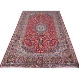 PERSIAN KASHAN WOOL CARPET, 11' 10" X 8' 2"A red ground, with flowering borders of geometric