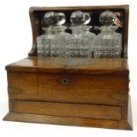 Oak tantalus with cupboard and drawer base housing three cut glass bottles, 34cm diameter : For